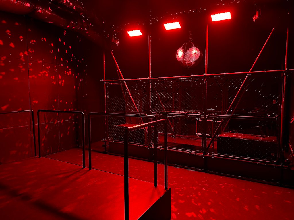 3F SECRET CLUB across the floor: red lights and a mirror ball, the wire-mesh DJ booth at the back