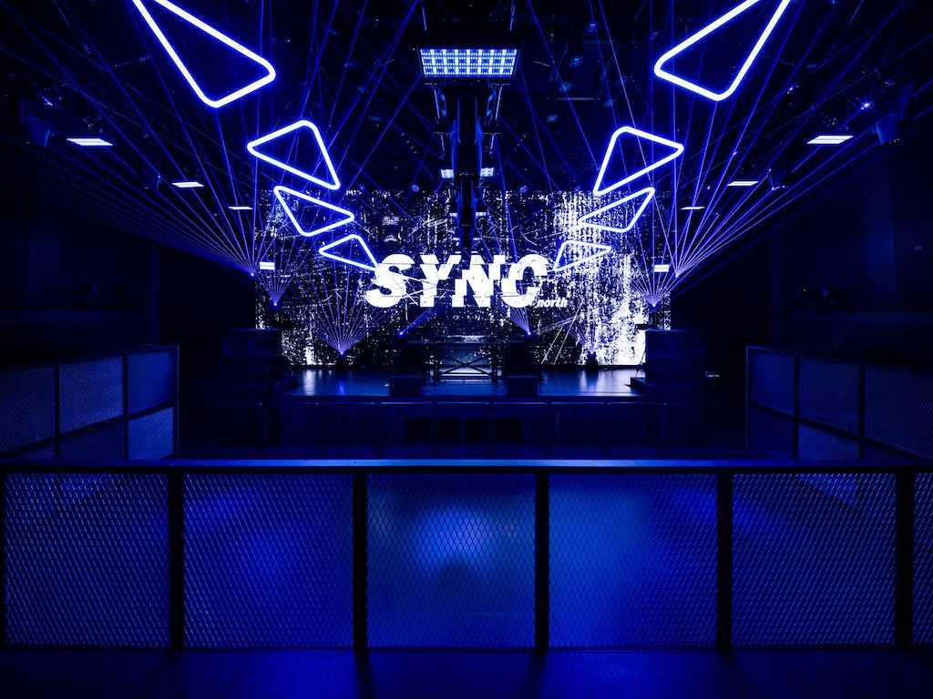 The main floor in blue light, the SYNC logo on the LED wall ahead