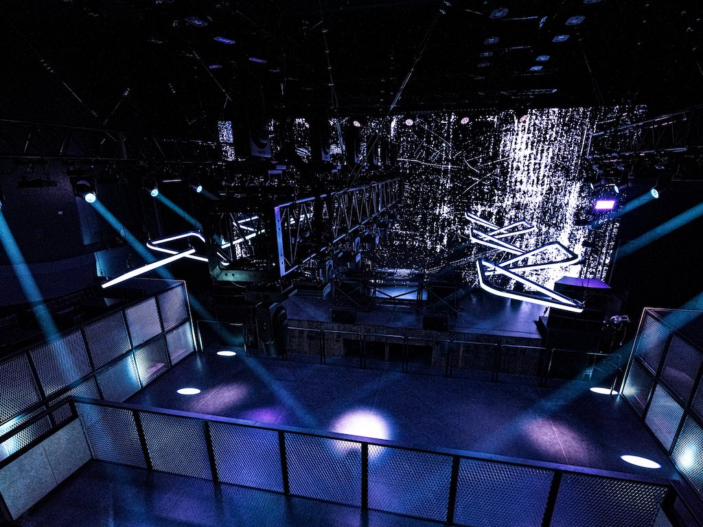 The floor seen from the upper level, spotlights on the floor and lighting rigged on trusses