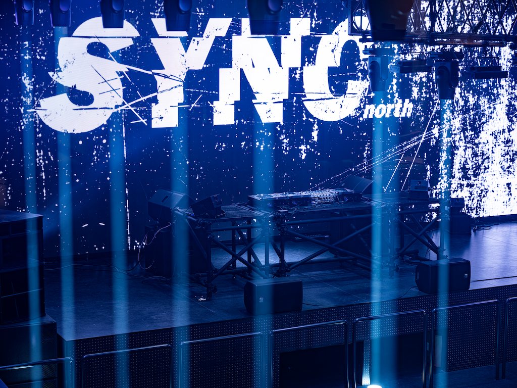 The blue-lit LED wall and the DJ booth on stage, with blue beams crossing