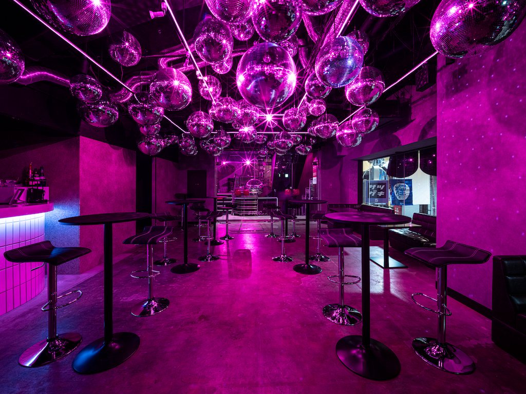 The bar and lounge under a ceiling packed with mirror balls: high tables and stools, the bar counter at the back