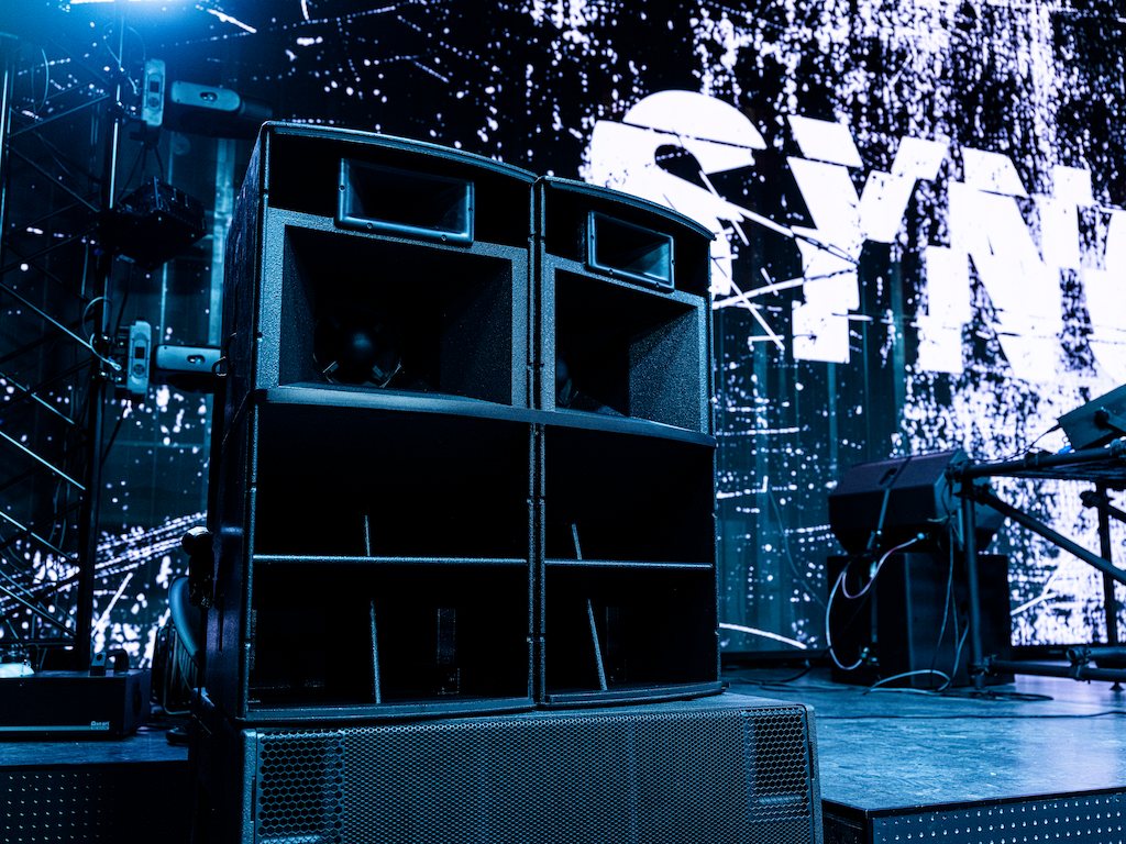 Speakers stacked beside the stage, the SYNC logo behind