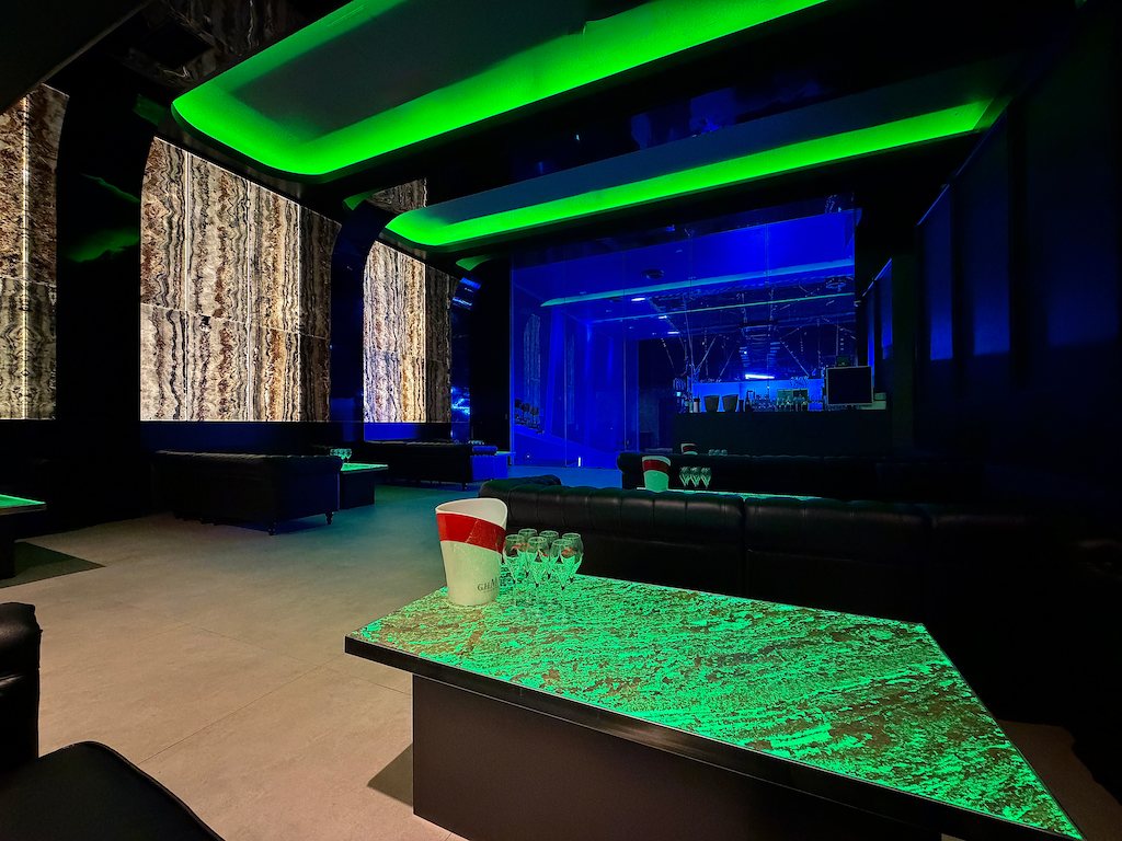 A table in 3F VVIP ROOM: illuminated tabletop, leather sofas, onyx walls and green cove lighting